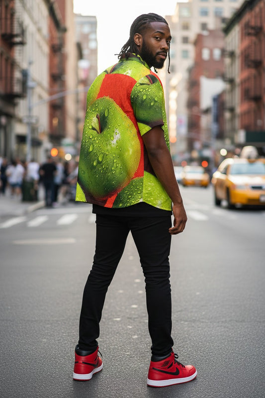 Man wearing a colorful shirt with a fruit design on a city street.
