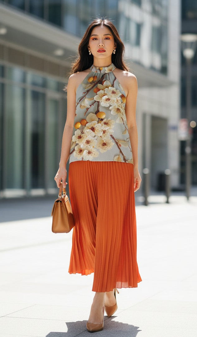 Woman in a floral top and orange skirt standing on a city street.