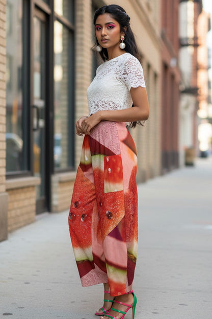 Woman in a white lace top and colorful pants standing on a city street.